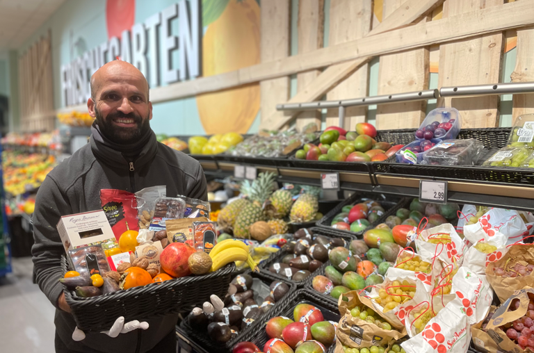 ein Mitarbeiter von EDEKA Georg mit einem Korb voll von Exoten, Nüssen, Datteln und Maronen