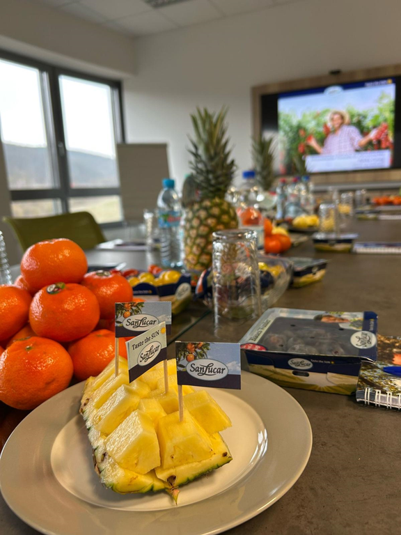 Ein Teller mit Ananasstücken und ein Berg Orangen auf dem Tisch bei der Schulung durch SanLucar in der Verwaltung von EDEKA Georg in Idstein