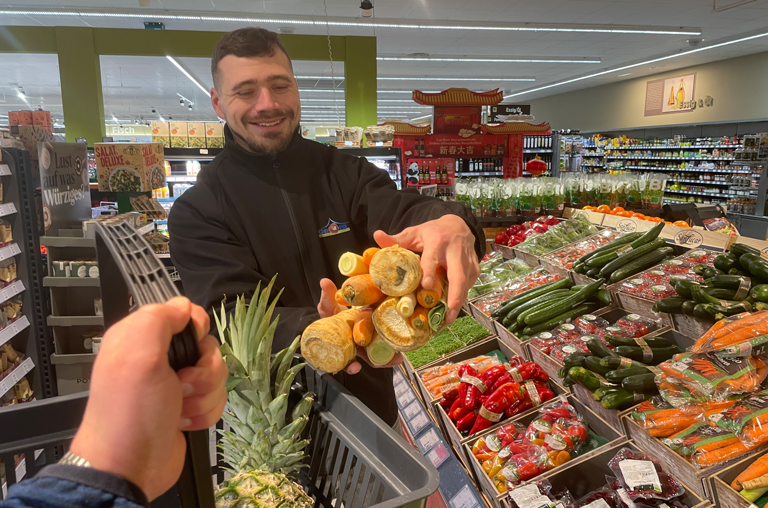 Mitarbeiter legt Produkte in den Korb eines Kunden