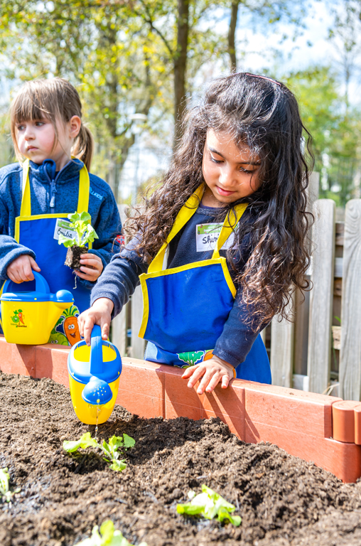 Gemüsebeete für Kids - ein Kind gießt die neuen Pflanzen