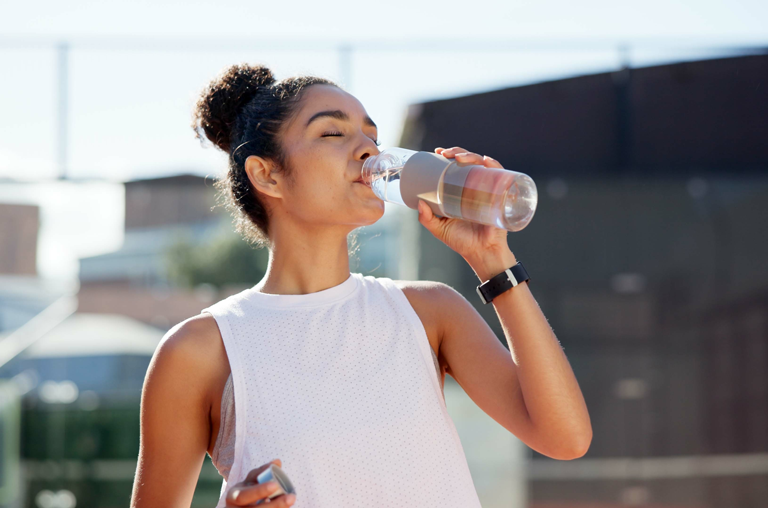 Eine Frau, die Sport macht, trinkt Wasser