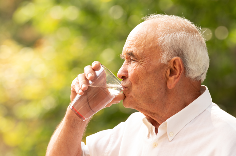 Ein älterer Herr trinkt Wasser